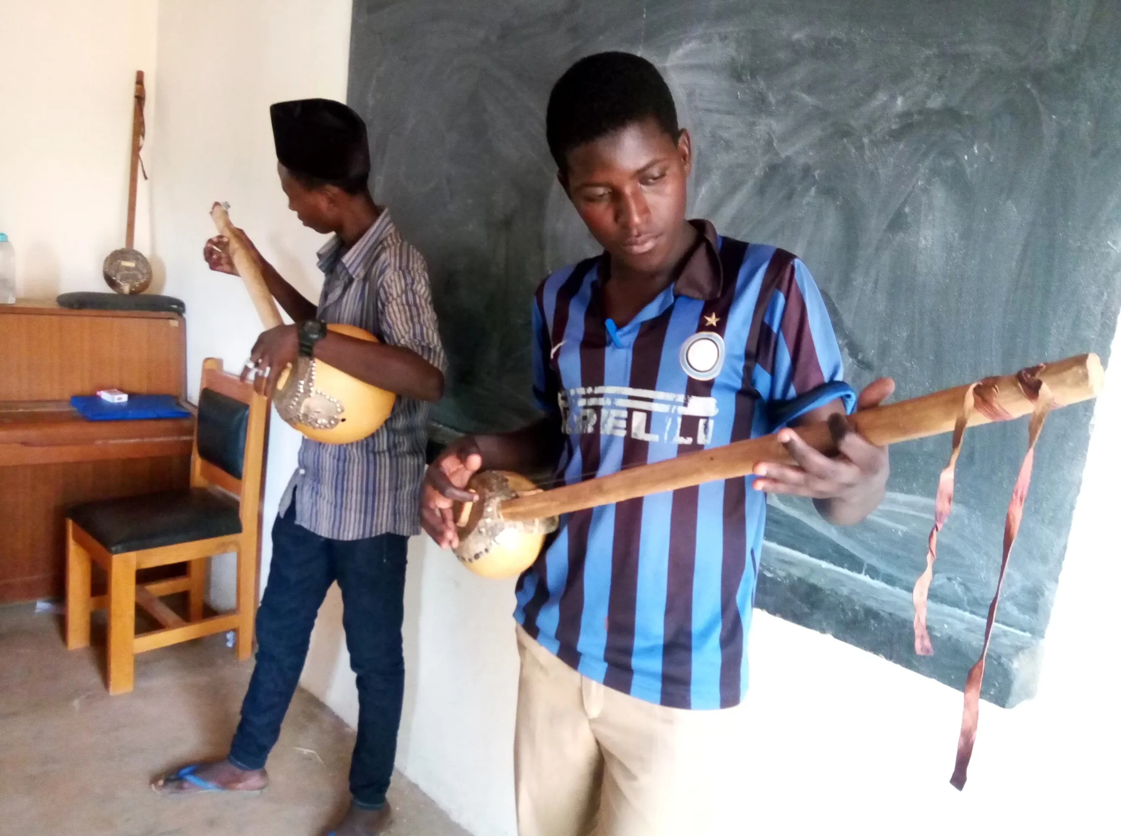 Two CFIM students practice playing gourimis that they built themselves
