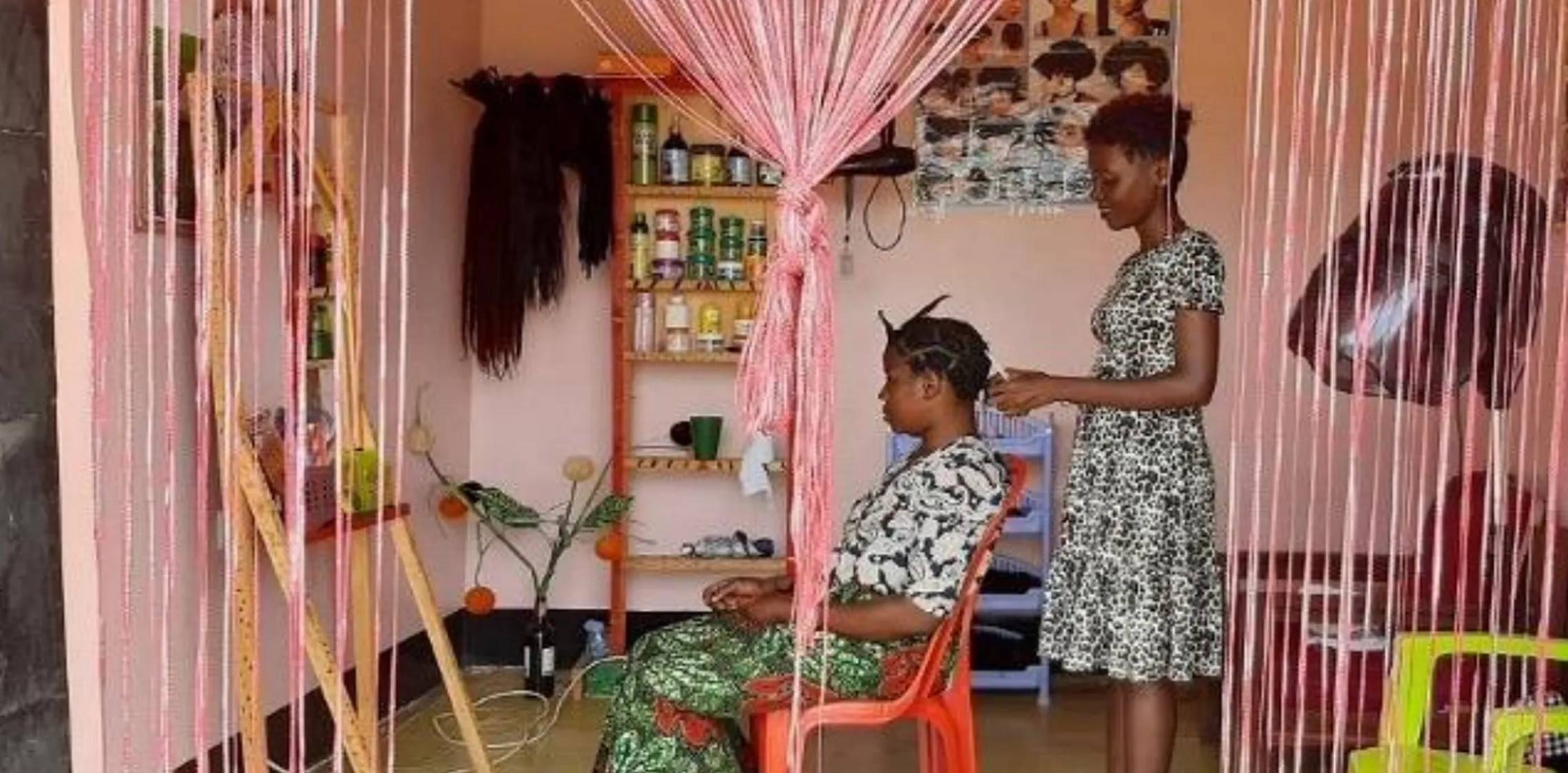 Woman cutting another woman's hair in a pink hair saloon.