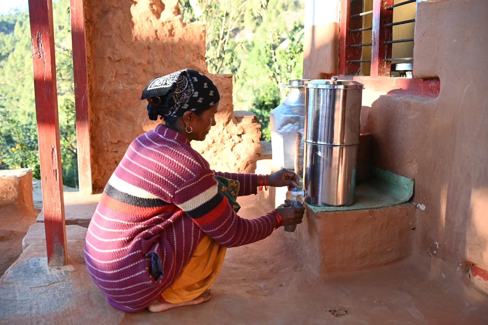 Woman from rural Nepal drinks water from a safely managed and secure water container.
