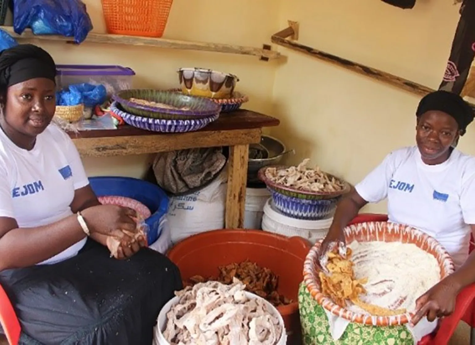 Mariam, assistent, puts sugar and milk powder on fritters. Amina bags them