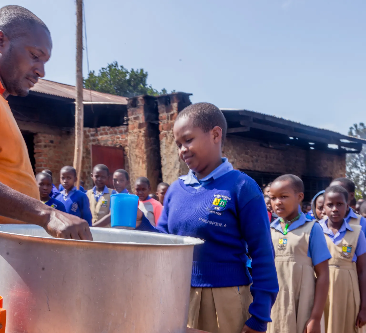 A girl in a queue to have a school meal as part of the TIDE programme in Uganda