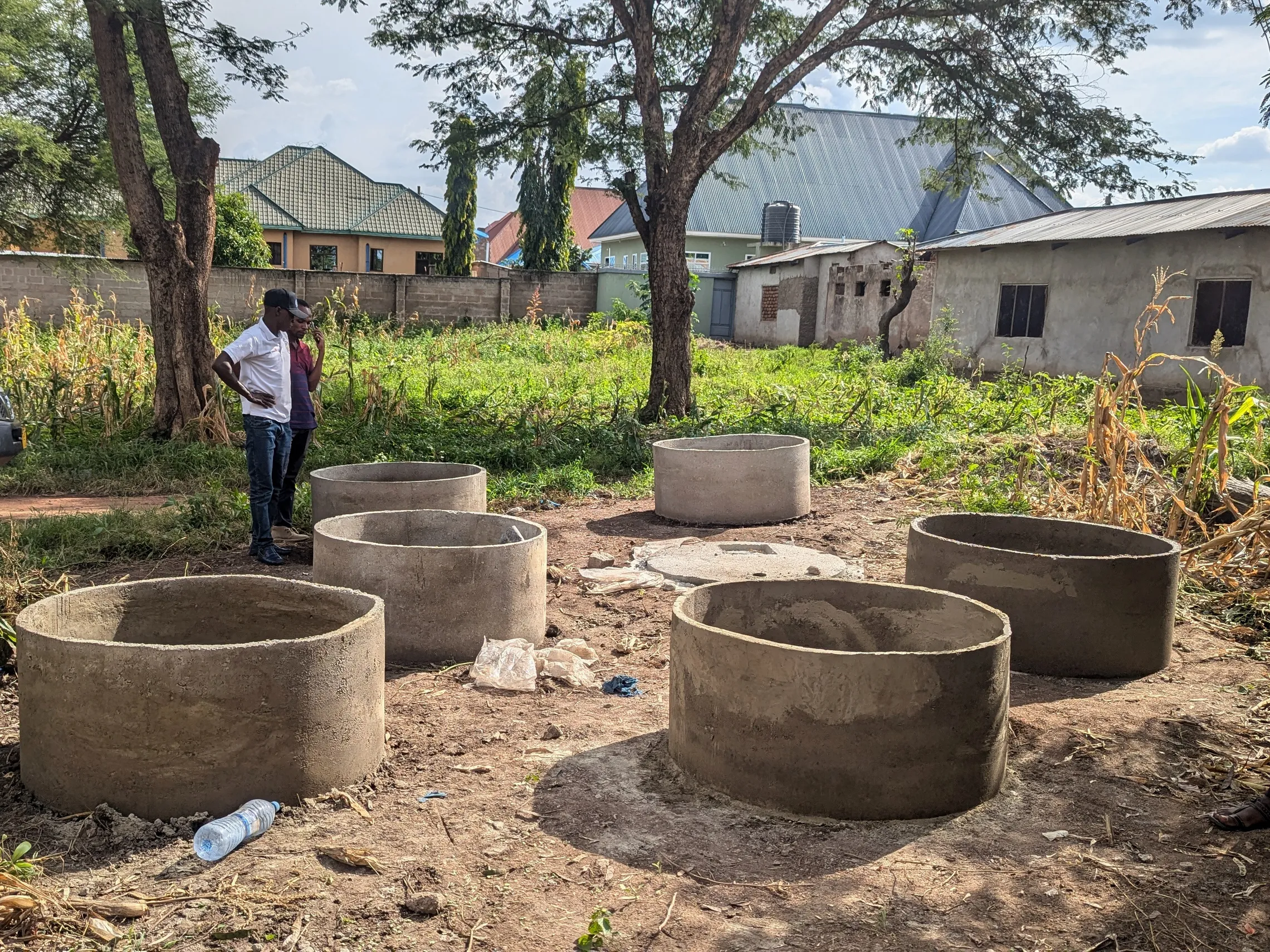 Concrete rings lay on the ground, awaiting toilet construction to begin in this town in Tanzania.