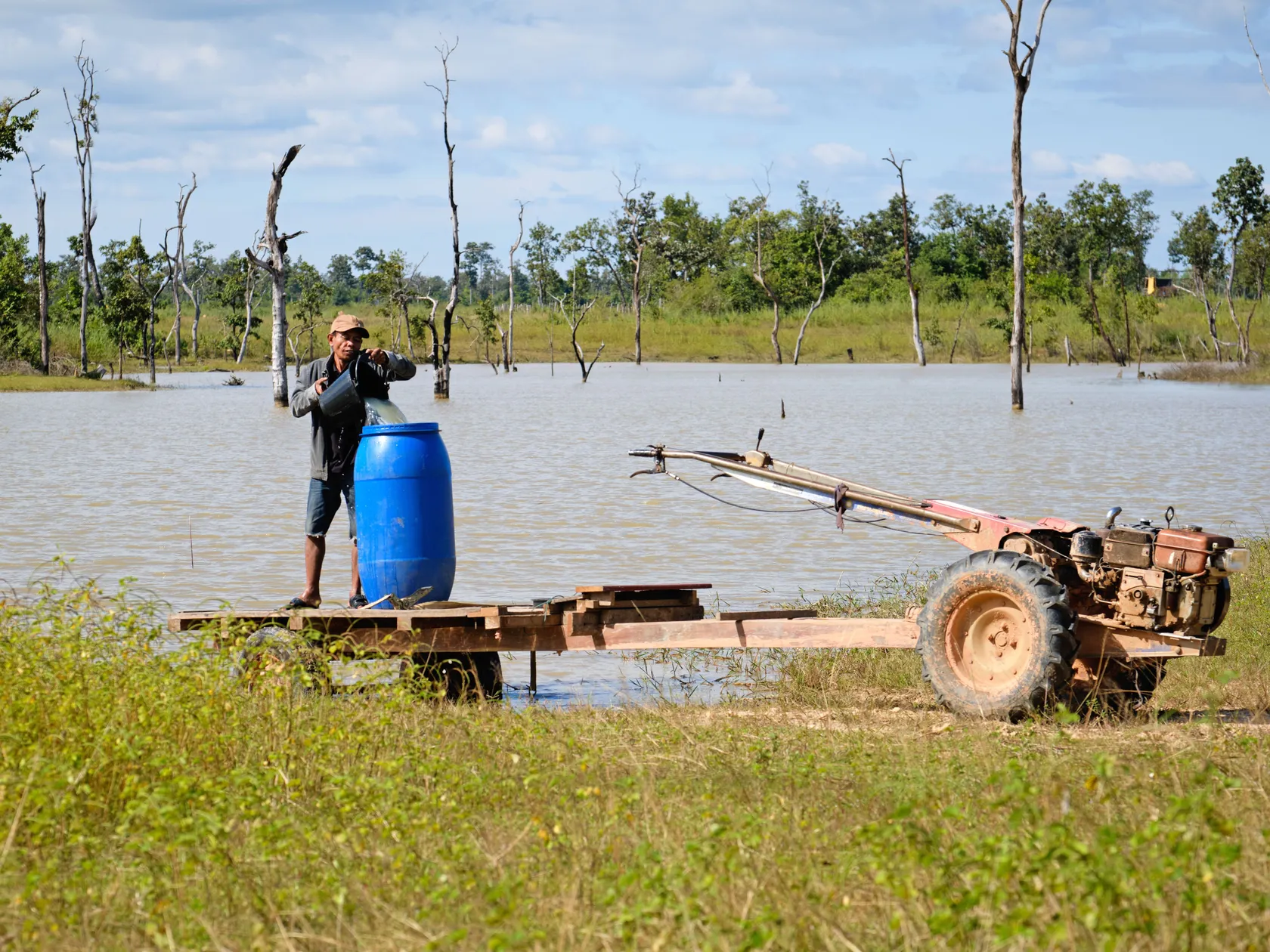 Man collects water from a pond in Savannakhet Province to transport back home.