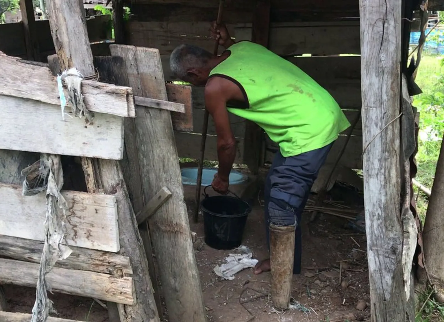 Inflexible makeshift wooden legs heighten the challenge of toilet use