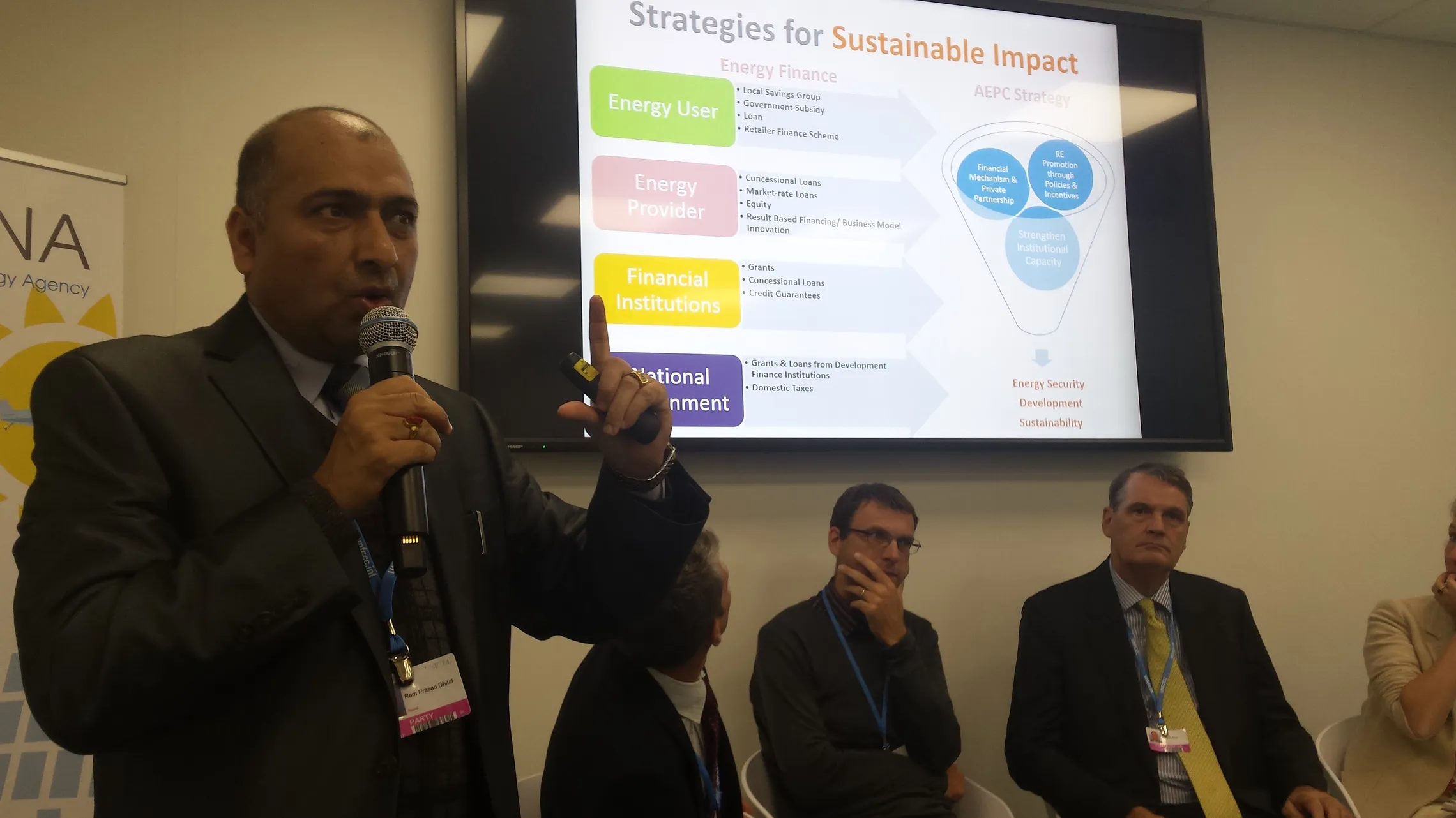 SNV side event panel discussion at COP23. A person is talking in the foreground. In the background there are people listening and a presentation slide about Strategies for Sustainable Impact