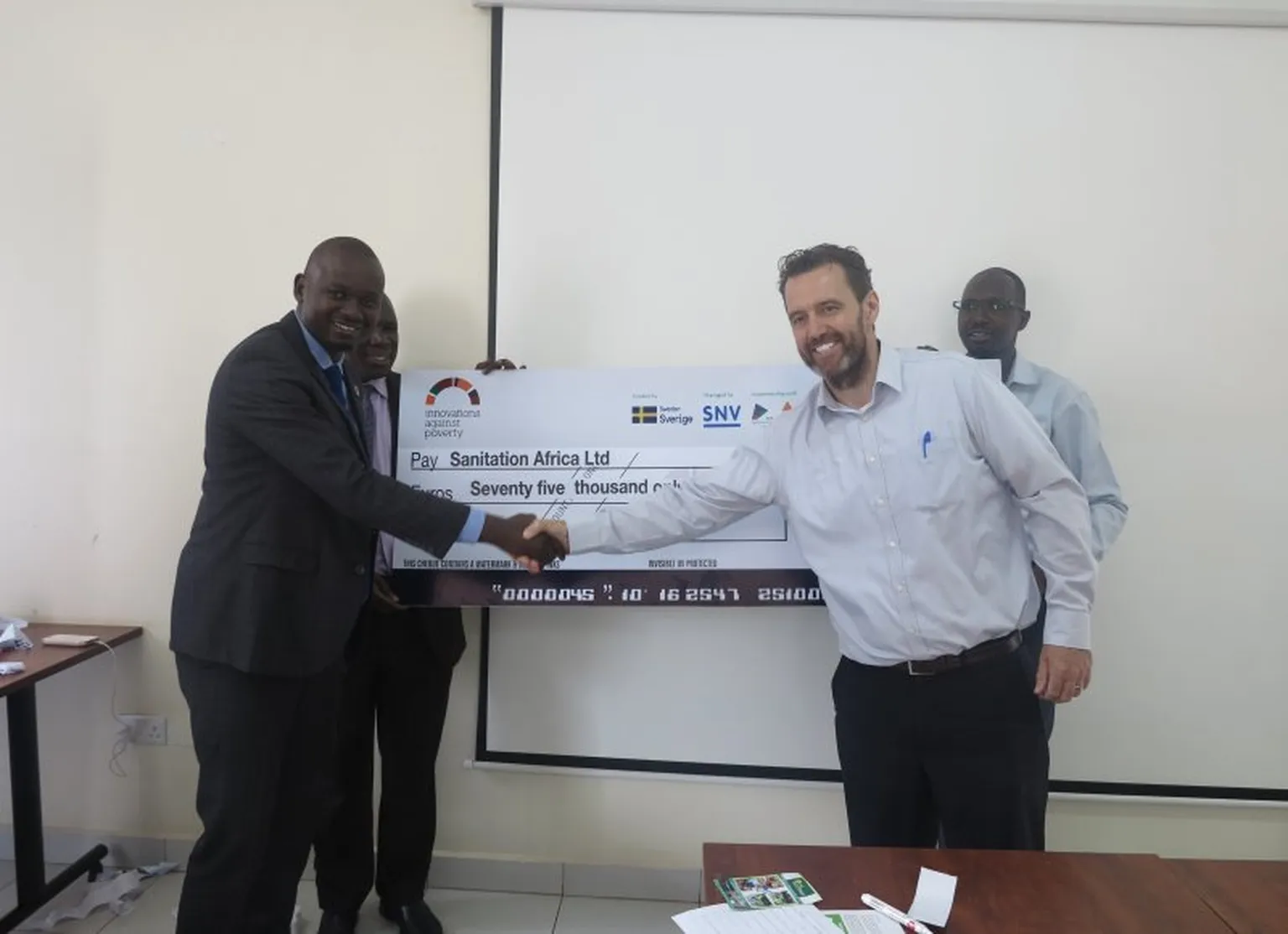 Samuel receives his IAP grant dummy cheque from SNV Uganda Country Director