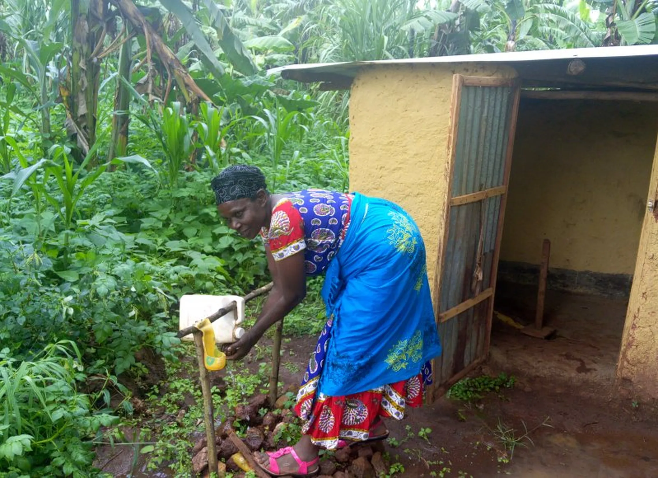 Ms. Mukamusoni’s with her improved latrine and tippy tap stand