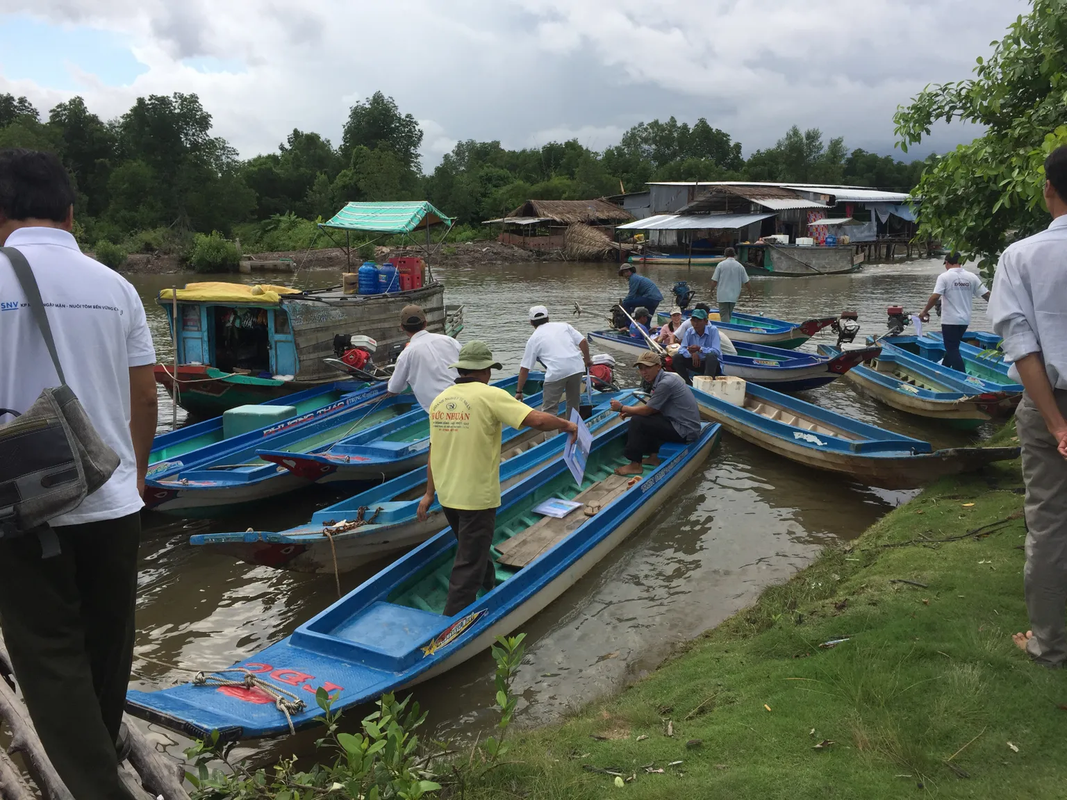 men standing and sitting on the boats in the small river